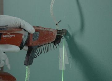 Carpenter with drill and concrete nails for wall usage.