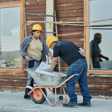 Construction workers using heavy duty wheelbarrow.