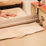 Worker preparing textile machine for sofa manufacturer.